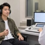 香港成年人士戴上測試耳機並手持反應掣進行純音聽力測試